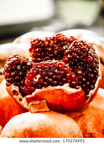 Organic bio pomegranate fruits at the farmers market. Pomegranate is one of Rosh Hashana (Jewish New Year) symbols. Still life. Closeup. Selective focus on the closest seeds. Aged photo.