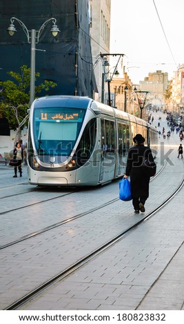 JERUSALEM, ISRAEL - FEBRUARY 19, 2014: Light Rail tram train and unidentified orthodox Jew walking on the rail on Jaffa Road street. Tram operates since 2011 and serves up to 130,000 people every day.