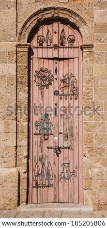 Old wooden door with iron figurative decoration (man travelling on donkey, etc). Architectural detail of Jaffa Clock Tower built in Ottoman period. Jaffa, Israel.