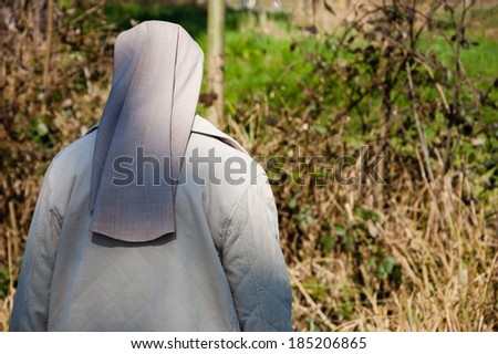 A nun in grey robe in the forest. A game of light and shadow. Religion and nature. Meditation background. Harmony, God in nature idea.