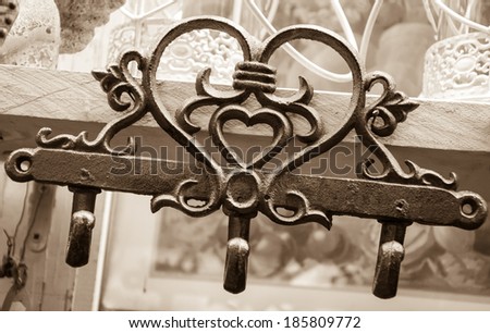 Heart shape hanger with three hooks for sale at market in Paris. Valentines Day background. Sepia.