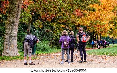 PARIS, FRANCE - OCTOBER 26, 2013: Unidentified people walk with sticks (Nordic walking) in Vincennes forest of Paris. Medical studies show that walking can reduce the risk of stroke in elderly people.