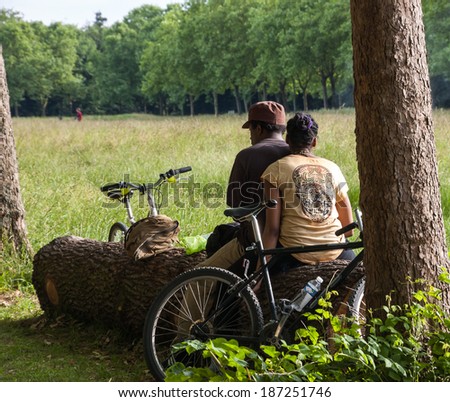 PARIS, FRANCE - JUNE 14, 2013: Unidentified man and woman rest and smoke in Vincennes park after biking.  Vincennes park is  the largest park of Paris which is very popular on weekends among Parisians