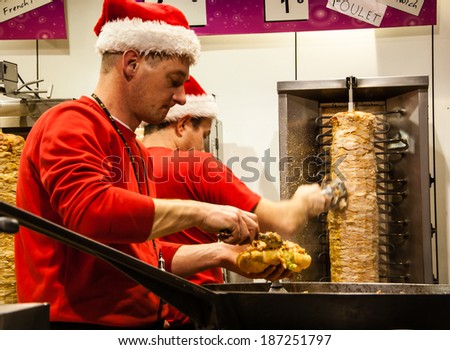 PARIS, FRANCE - NOVEMBER 30, 2013: Two unidentified men in Santa Claus hats cook and sell kebab at Christmas market.
