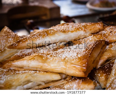 Borek (puff pastry pie with cheese coated with sesame seed) served in traditional oriental restaurant. Selected focus on the sesame seeds of the closest burek.