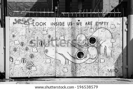 LONDON, ENGLAND, UK - MAY 4, 2014: Black and white graffiti representing modern life (created by MIIIO) on the gate in Brick Lane area. Urban art in this area attracts tourists from all over the world