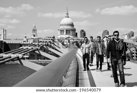 LONDON, ENGLAND, UK - MAY 3, 2014: Tourists walking across the Millennium Bridge, which was opened in 2000. St Paul's cathedral is seen at backgrounds.