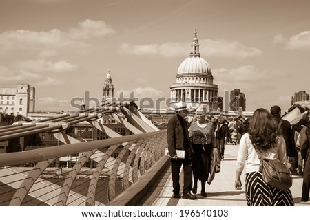 LONDON, ENGLAND, UK - MAY 3, 2014: Tourists walking across the Millennium Bridge, which was opened in 2000. St Paul\'s cathedral is seen at backgrounds.