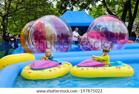 LONDON, ENGLAND, UK - MAY 5, 2014: Unidentified kids sail in inflatable boats and zorb inside large balls on water during annual Canalway Cavalcade, a unique waterways festival of traditional boats.