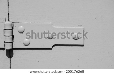 A hinge on old painted wooden door. Aged photo. Black and white.