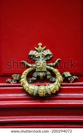 Royal style doorknocker on red door. Paris, France.