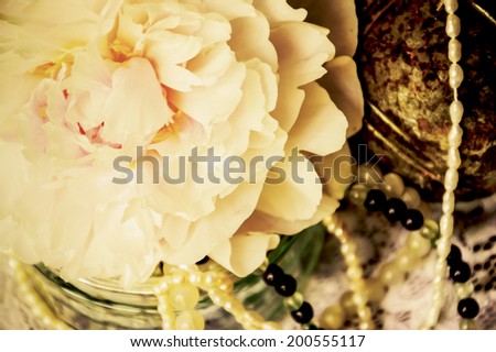 Vintage background with pink peony, jewels in glass jar and old rusty iron ball on the lace. Light glow. Aged photo. Sepia.