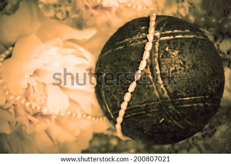 Vintage background with pink peony, jewels in glass jar and old rusty iron ball on the lace. Aged photo.