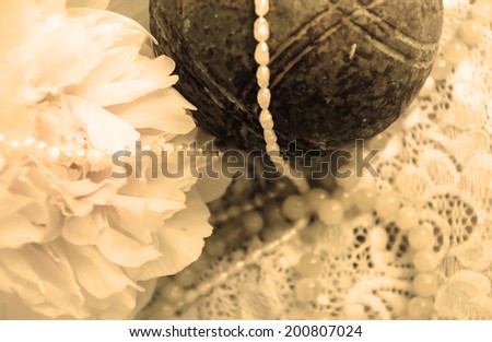 Vintage background with peony, jewels and old rusty iron ball on the lace. Aged photo. Sepia.