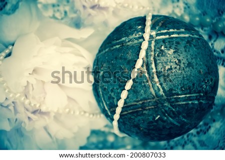 Vintage background with pink peony, jewels and old rusty iron ball on the lace. Aged photo.
