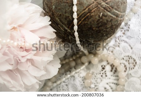Vintage background with pink peony, jewels and old rusty iron ball on the lace.