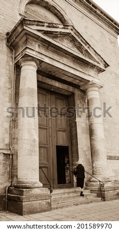 RUE, FRANCE - APRIL 13, 2014: Unidentified senior woman with traditional boxwood branch bouquets enters to the church of Holy Spirit on Palm Sunday (Dimanche des Rameaux) .