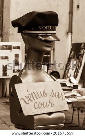 Female mannequin wearing a black driver cap. Still life at flea market in Paris. Aged photo. Sepia.
