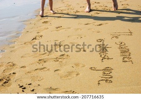 A sentence written on the sand of a beach: THE SUMMER IS ALMOST GONE, footprints and male and little boy foots . Vacation end / back from holiday / back to the work or school concept.