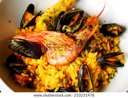 Seafood paella with chicken casserole and chorizo sausage in rustic restaurant.