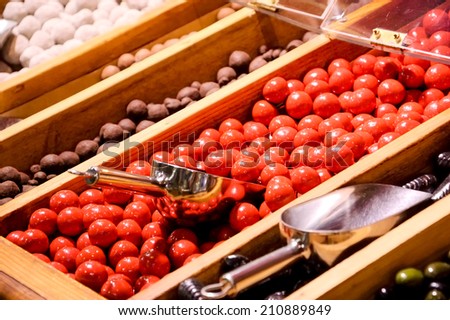 Red sugar iced chocolate balls and other candies in candy shop. Selective focus on the red candies.