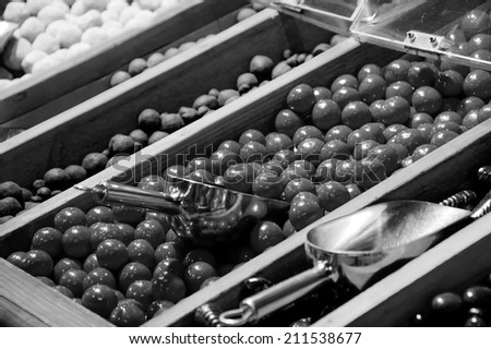 Sugar iced chocolate balls and other candies in candy shop. Selective focus on the chocolate balls. Aged photo. Black and white.