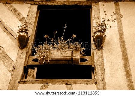 Old half timbered house house decorated with flowers.  Dol de Bretagne, Brittany, France. Aged photo. Sepia.