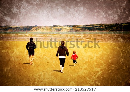 Young family (mother, father and little child) running towards the sea. Back view. Brittany, France. Retro aged photo with scratches.