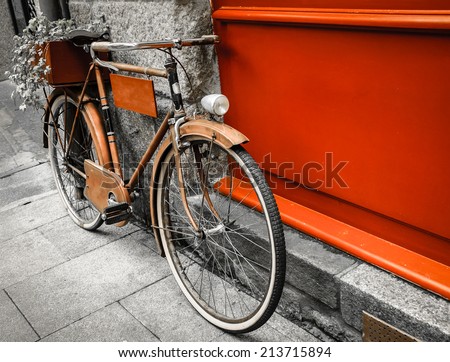 Rusty vintage red bicycle leaning with on red wooden board (useful for entering a text advertisement, menu etc) and carrying plants in wooden box as decoration. Retro aged photo.