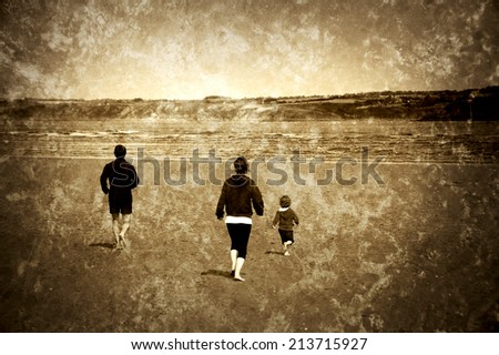 Young family (mother, father and little child) running towards the sea. Back view. Brittany, France. Retro aged photo with scratches. Sepia.