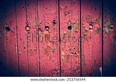 Texture of weathered wooden lining boards with peeling violet paint and rusty nail heads. Vignette.