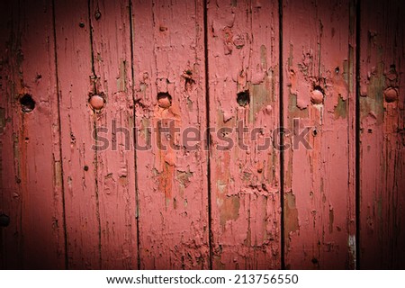 Texture of weathered wooden lining boards with peeling pink paint and rusty nail heads. Vignette.