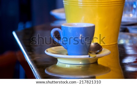 Coffee cup and its reflection on the shiny counter of the typical Parisian bar. Yellow sugar tin at backgrounds (also reflected on the counter and in the saucer).