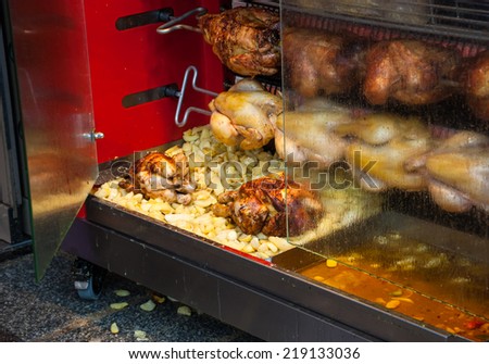 Rotisserie chicken and potatoes near the entrance to the butcher shop in Paris (France).
