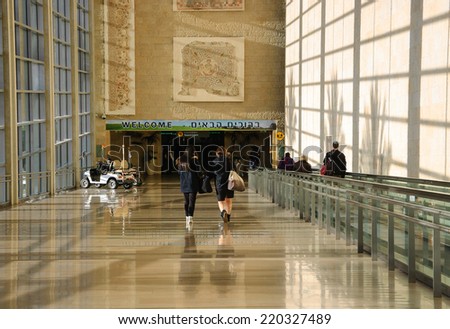 TEL AVIV, ISRAEL - FEBRUARY 13, 2014: Tourists arriving to Israel and Israeli citizens coming back home at the Ben Gurion International Airport going towards WELCOME sign placed under ancient mosaic.