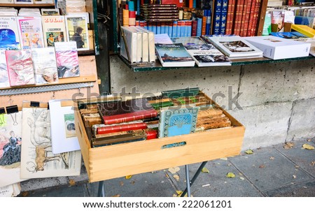 PARIS, FRANCE - OCTOBER 4, 2014: Bouquiniste stands over Seine river near Notre Dame cathedral. Selling books on the banks of the Seine began around the 16th century.