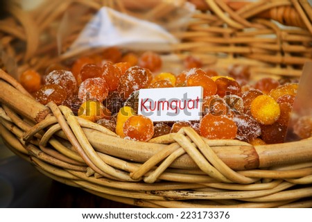 Dried sugared kumquat in wicker basket at the farmers organic market in Paris. Label with fruit name.