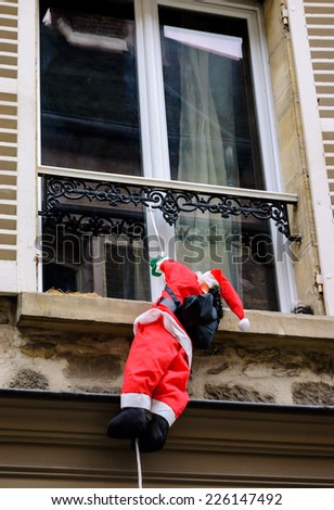 Santa Claus climbing up a wall into a window. Traditional Christmas decoration.