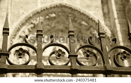 Forging fence of Cathedral in Chartres (France). Selective focus on the arrows of the fence. Aged photo. Sepia.