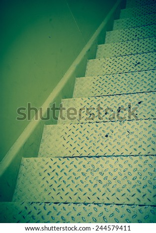 Yellow steel diamond plate stairs and yellow concrete wall. Blue toned photo.