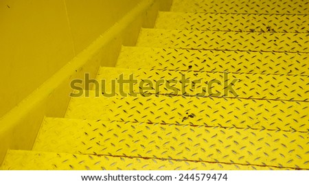 Yellow steel diamond plate stairs and yellow concrete wall.