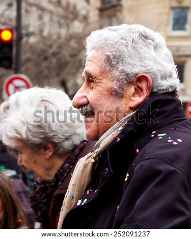 PARIS, FRANCE - MARCH 3, 2014: Unidentified senior spectator of the Carnival in Paris covered with the confetti. Carnaval de Paris is annual event, which history starts from the sixteenth century.