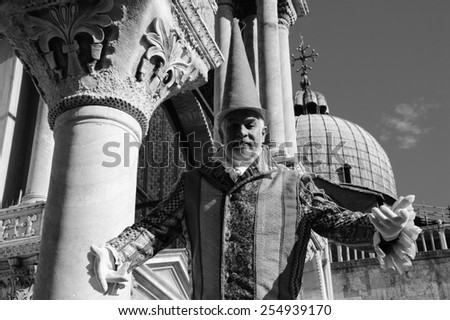 VENICE, ITALY - FEBRUARY 16, 2015: Unidentified man in carnival costume in St Mark\'s Square (St Mark\'s Basilica at background). Venice Carnival is annual event which ends on Shrove Tuesday.