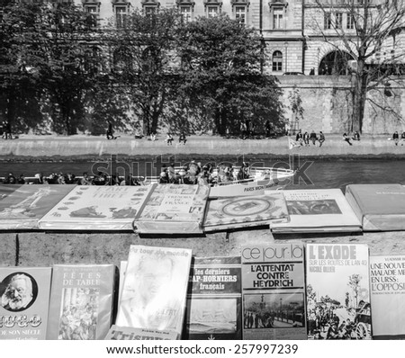 PARIS, FRANCE - APRIL 20, 2013: Bouquiniste stands over Seine river and tourist boat. Selling books on the banks of the Seine began around the 16th century.