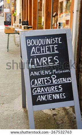 Signboard outside old books store in France. Text in French meaning: Secondhand bookseller buying old and modern books, postcards, ancient prints.
