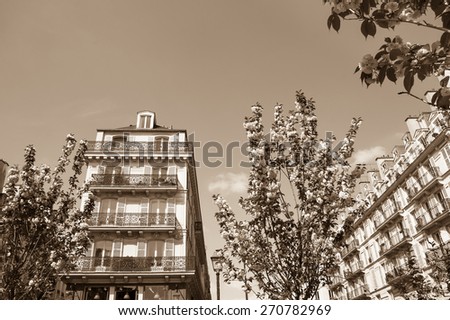 Spring in Paris. Typical Parisian buildings (Marais quarter) and blossoming trees. Aged photo. Sepia.