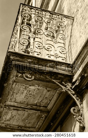 Old balcony. Rusty wrought iron railing with floral curling pattern. Weathered wooden base with peeling paint. Mers-les-Bains (Picardy, France). Aged photo. Sepia.