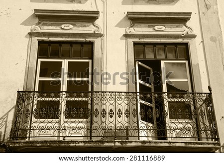 Balcony with wrought iron railing. Old typical house in Evora, Portugal. Historic Centre of Evora is a UNESCO World Heritage Site. Aged photo. Sepia.