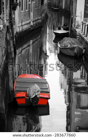 Narrow canal in Venice. Boats and reflection of houses in the water. Selective focus on the  reflection. Retro aged photo.