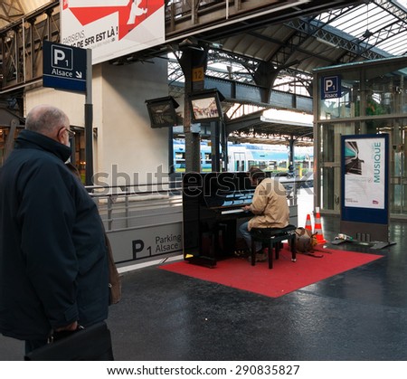 PARIS, FRANCE - DECEMBER 15, 2013: Man playing piano at Gare de l\'Est (Paris Est train station). Several pianos are found at Parisian train stations allowing the passengers to play for their pleasure.